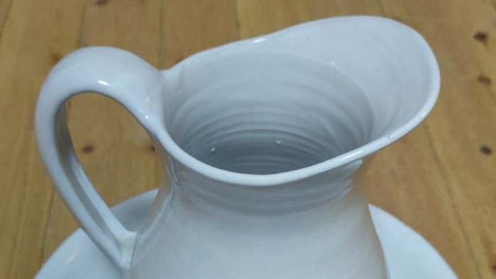 Weißer Krug auf Untertasse auf Holztisch