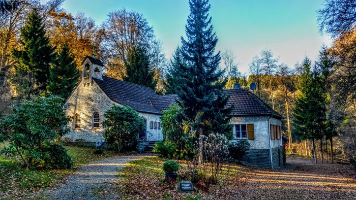 Zwei gemütliche Häuser in ländlicher Umgebung mit hohem Baum und Garten.