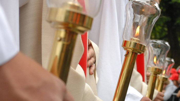 Eine Gruppe von Menschen hält Fackeln in weißen Roben