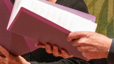 Zwei Personen reichen sich einen Stapel Unterlagen.