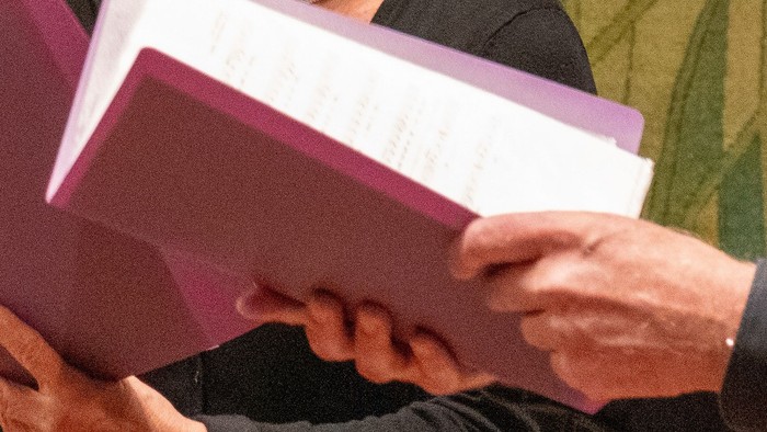 Zwei Personen reichen sich einen Stapel Unterlagen.