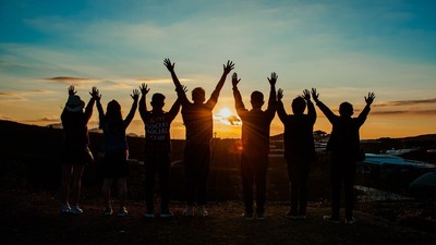 Eine Gruppe von Menschen feiert bei Sonnenuntergang