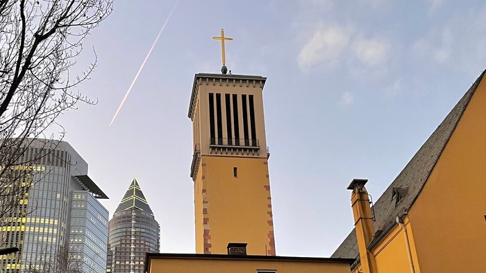 Altes Kirchengebäude vor moderner Stadtlandschaft