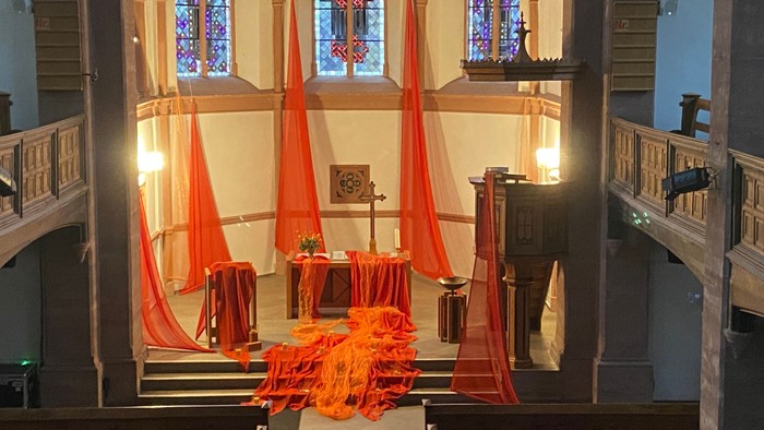 Oranges und weißes Dekor in Kirche mit hohen Fenstern