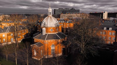 Bygning med kuppel i en bydel med træer og andre bygninger.