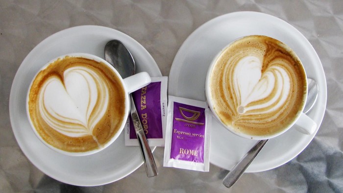 Zwei Cappuccinos mit Milchherz und Zuckerpäckchen