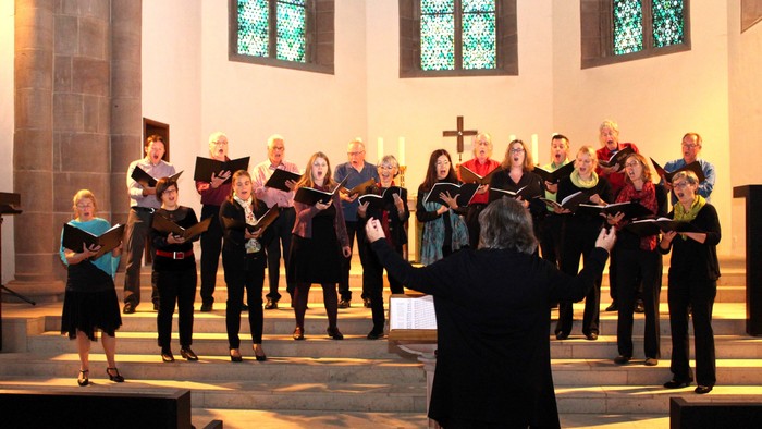 Kirchenchor singt vor farbenprächtigen Buntglasfenstern