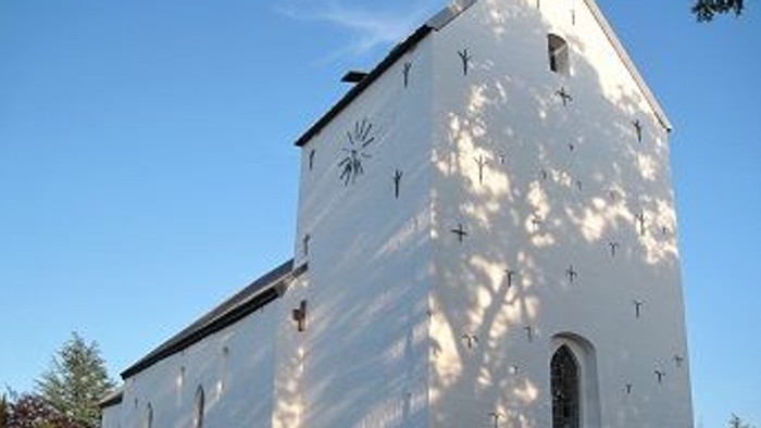 Et hvidt kirkebygning med klokketårn og en lille portal.