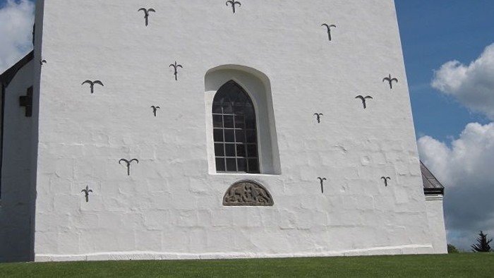 Hvid kirke med kryds på vægge og vindue.