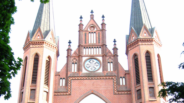 Große Ziegelkirche mit zwei Türmen und einem großen Rosettenfenster
