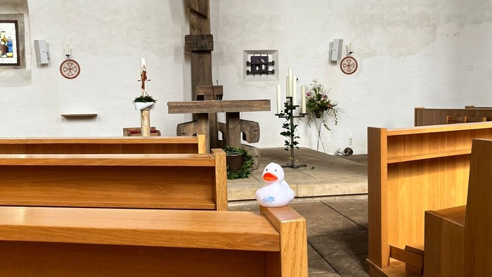 Holzbänke in Kirche mit Kreuz und Kerzen