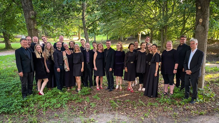 En gruppe af mennesker står sammen i en park, alle klædt i sort