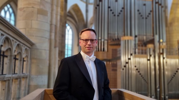 Mann in Anzug steht vor Kirchenorgel