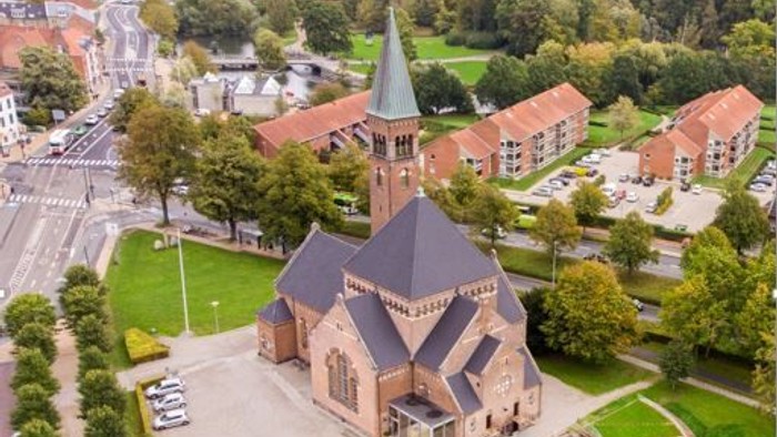 En kirke med tårn i et boligområde med huse og træer