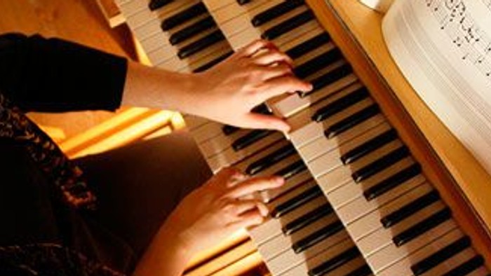 Junges Mädchen spielt Klavier und liest Noten.