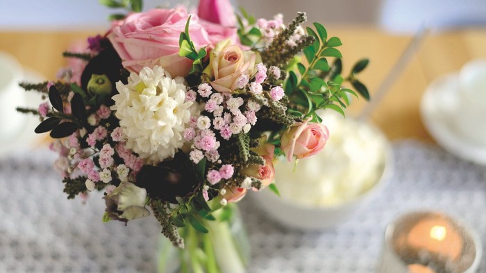 Ein Blumenstrauß in einer Vase auf einem Tisch mit Kerze und Schale