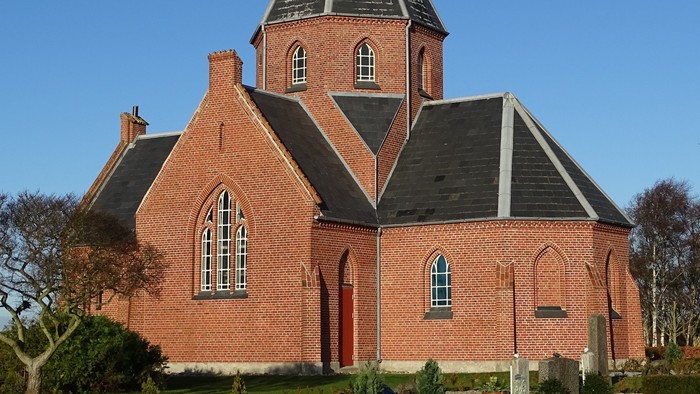 Røde murstenskirke med spiret og vindrosen.