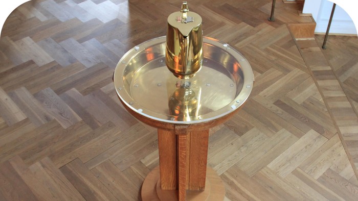 Gul og sølv drikkefontæne på trægolvet