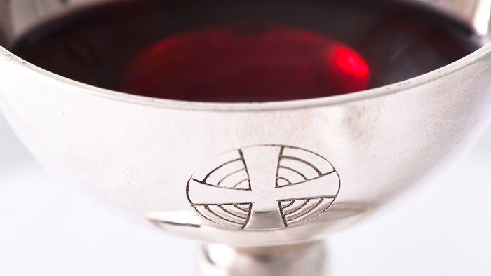 En sølv kalix med mønster og rød væske.