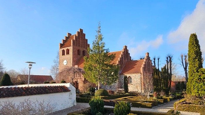 En smuk have med formede hegn og en stor kirke i baggrunden