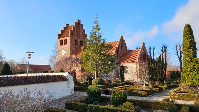 En smuk have med formede hegn og en stor kirke i baggrunden