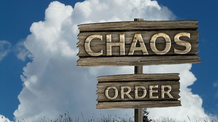 Holzschilder mit den Aufschriften Chaos und Ordnung vor blauem Himmel