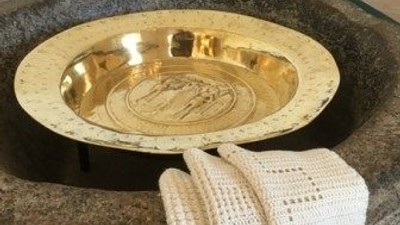 En stor, rund steintop med en gylden skål og et hvidt strikket håndklæde.