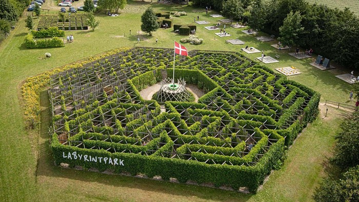 Et stor hegnemaze med flag i midten og skiltet "LabyrintPark" foran.
