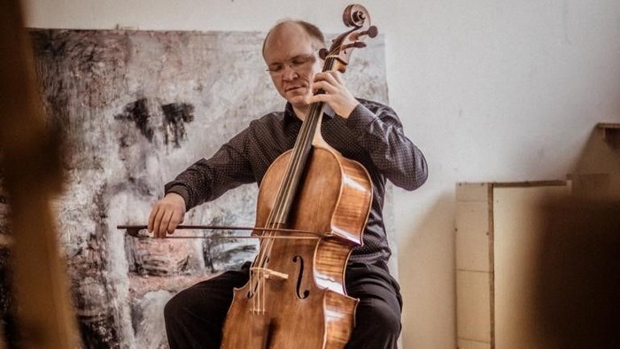 Mann spielt Cello in einem kargen Raum
