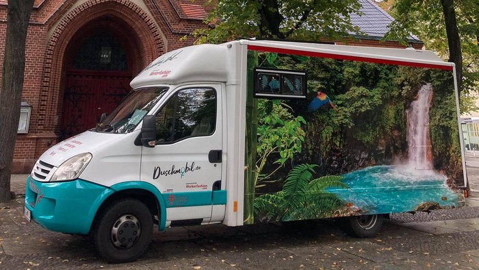 Weißer Lieferwagen vor Backsteingebäude mit Turm