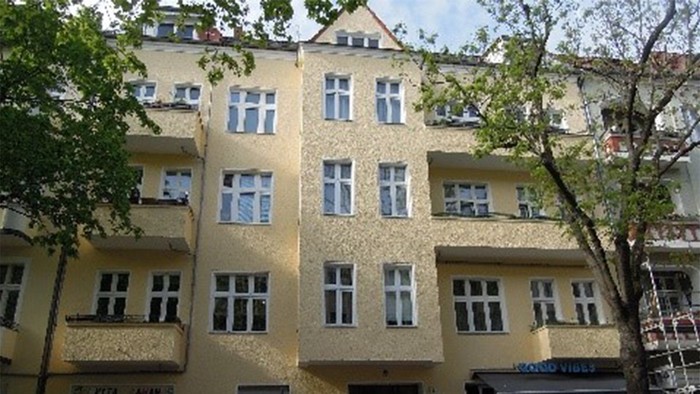 Gelbe Wohngebäude mit vielen Fenstern und Bäumen davor