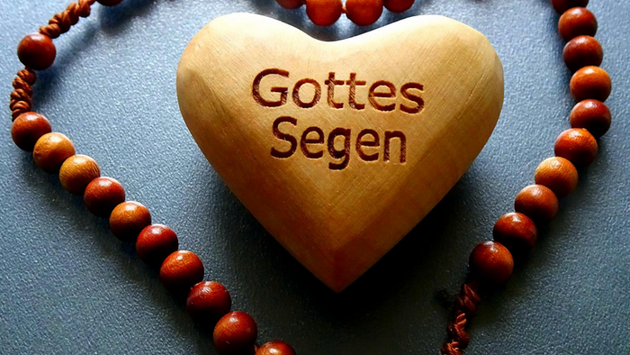 Holzherz-Anhänger mit „Gottes Segen“, umgeben von einem herzförmigen Rosenkranz aus Holzperlen.