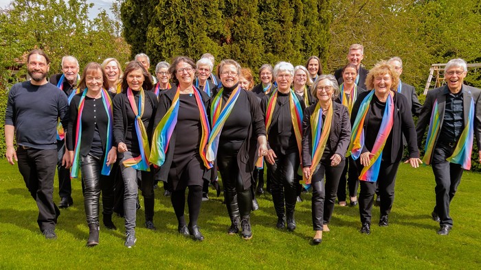 Eine Gruppe von Menschen posiert im Garten, alle mit Regenbogenfahnen geschmückt