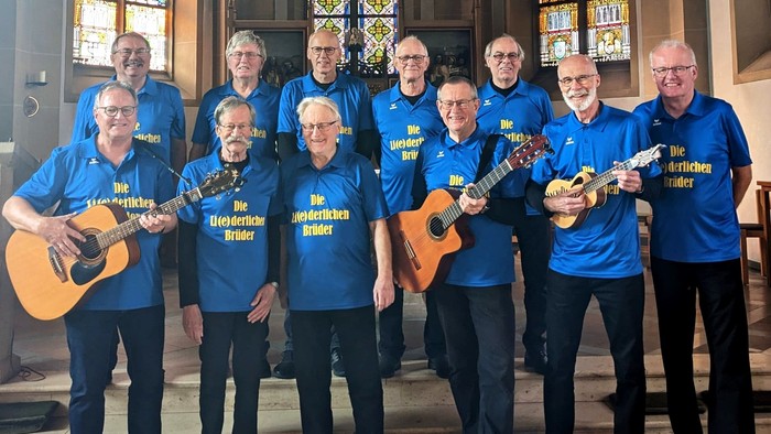 Eine Gruppe von Menschen in blauen T-Shirts spielt Gitarren und Ukulelen in einer Kirche.