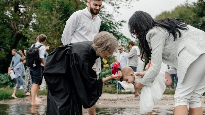 Eine Gruppe von Menschen steht in einem flachen Gewässer und sammelt Müll mit schwarzen Säcken.