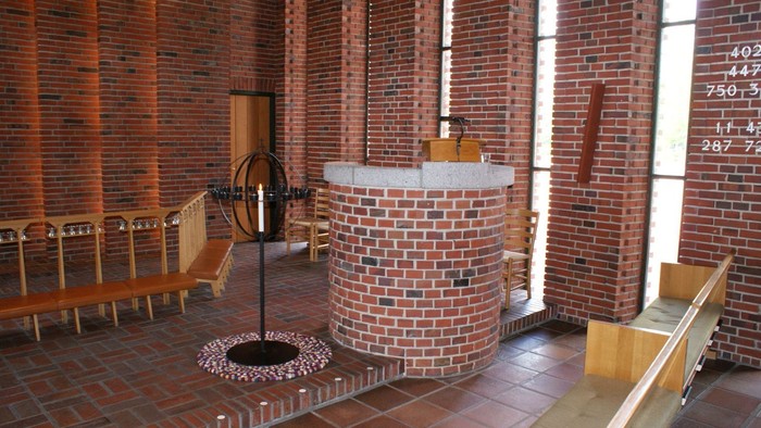 Kirken har murstensvægge og træbænke.