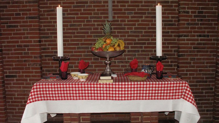 Bord med røde og hvide tæpper, lysstake, frugtkorbe og røde hjerter