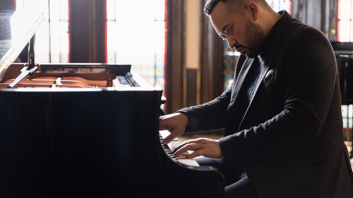 Man playing piano in dimly lit room.