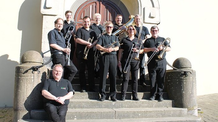 Musiker posieren mit Instrumenten auf Treppen.