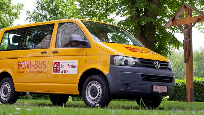 Ein gelber VW-Bus mit der Aufschrift "BONI-BUS" steht auf einer Wiese.