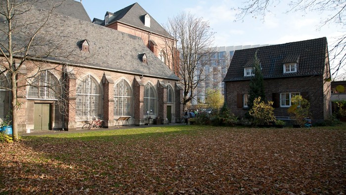 Altes Backsteingebäude mit spitzen Fenstern und modernes Haus daneben