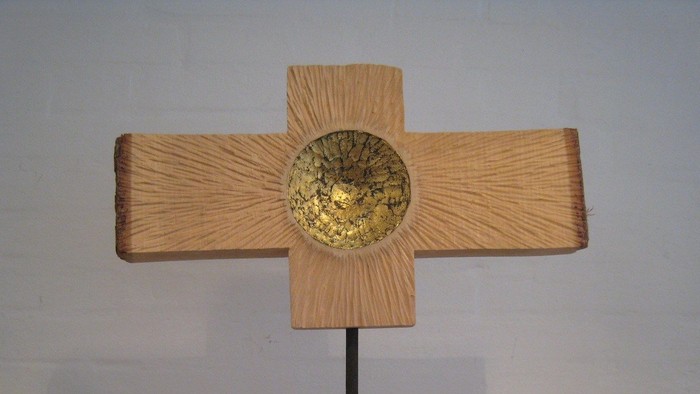 Et kryds af lysebrun træmateriale med en guldfarvet midterdel