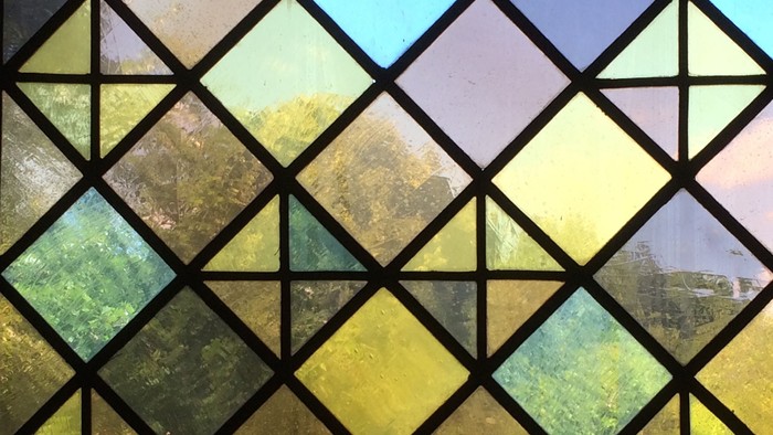 Farbenfrohes Fenster mit geometrischen Mustern und Aussicht auf Bäume