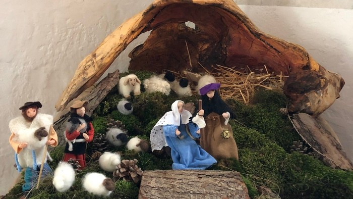 Weihnachtskrippe mit Figuren und Tieren in einer Stallkulisse