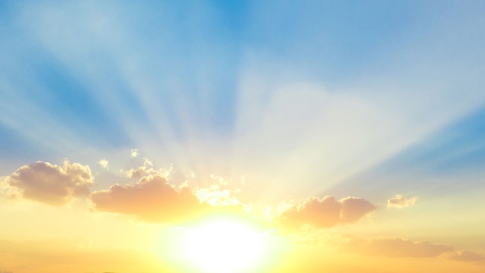 Solopgang med lyse skyer og blå himmel