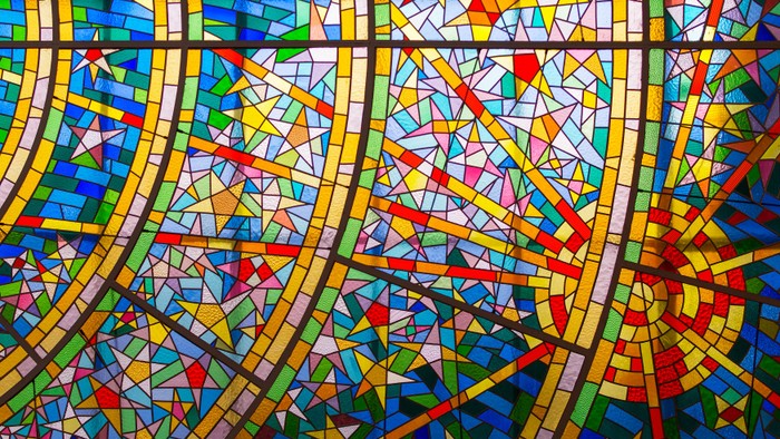 Farverige glassmosaik med geometriske mønstre og kurver.