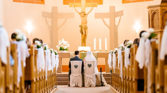 Ein Brautpaar bei der Trauung in einer Kirche vor dem Altar.