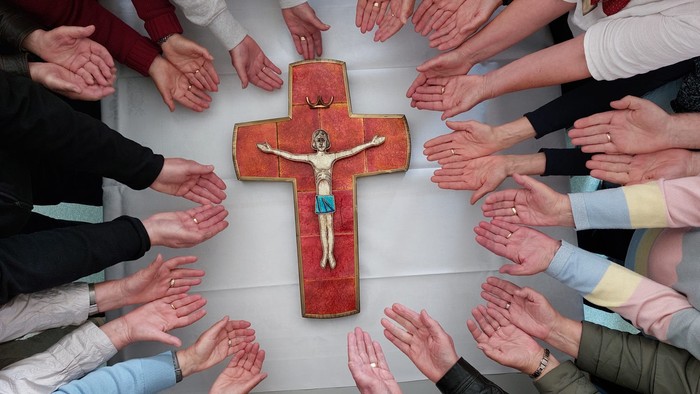 Eine Gruppe von Menschen betet um ein Kreuz mit einem Jesusbild.