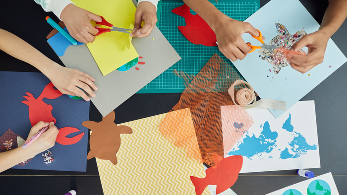 Børn laver papirklip med farvede papir og saks.