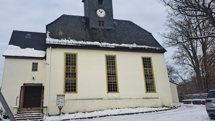 Weißes Kirchengebäude mit Uhrturm und Schnee